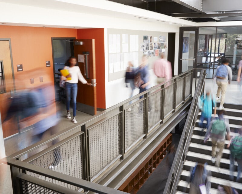 A busy secondary school corridor and staircase shown at class change-over time with lots of students moving around.