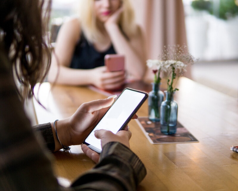 Young woman using smart phone in a cafe or restaurant for checking social media.