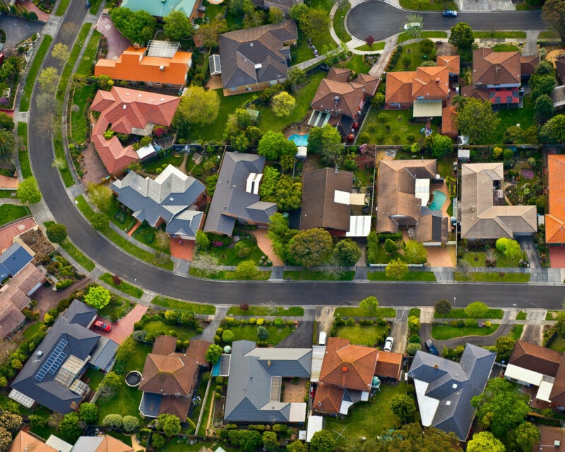 Arial view of about 20 houses in the suburbs of a typical large Australian city.